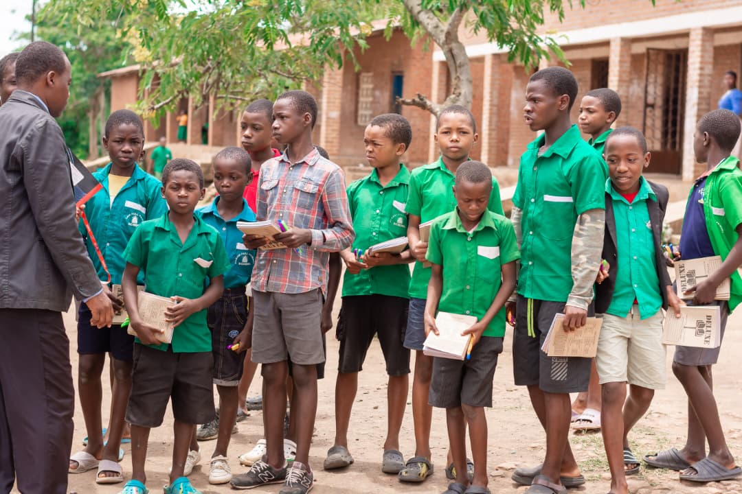Students in green uniforms lined up for materials
