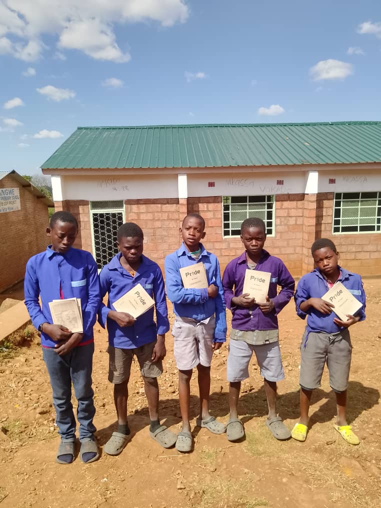 Six boys in school uniforms with Pride exercise books at school