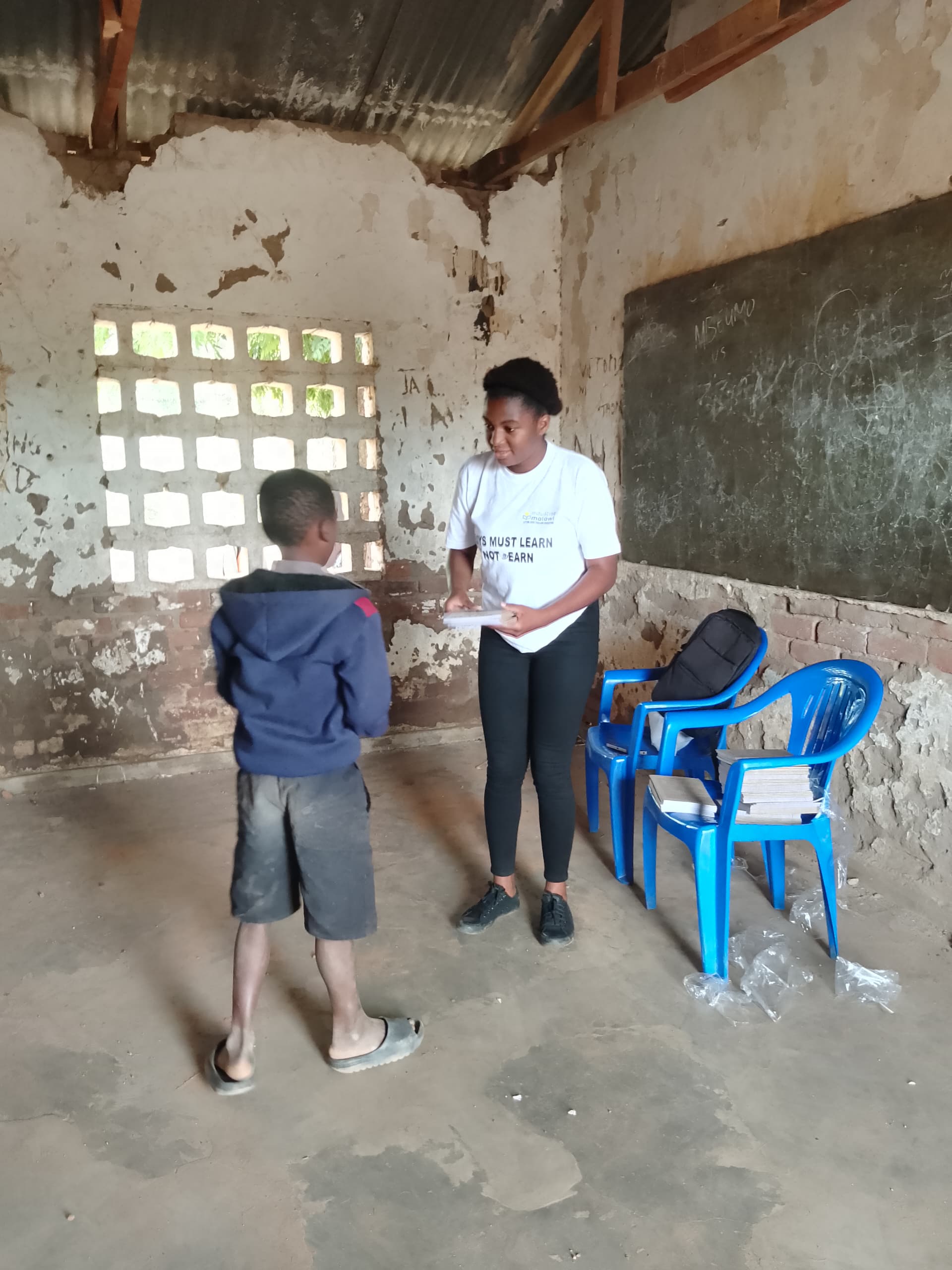 EduRise staff distributing materials to a boy in classroom