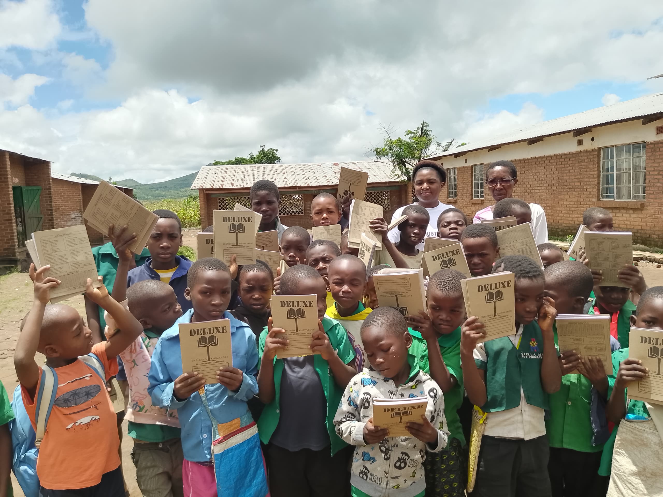 Large group of children with notebooks celebrating